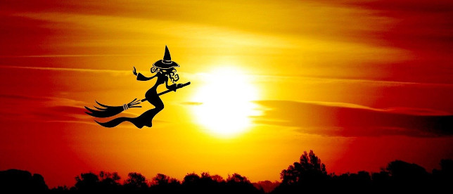 Hexe auf Hexenbesen fliegt in den Sonnenuntergang